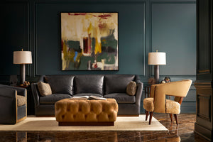 Deep green room with brown leather sofa and tufted brown ottoman and two leather side chairs