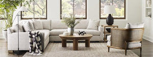 White sectional in front of windows sitting opposite a caned back armchair
