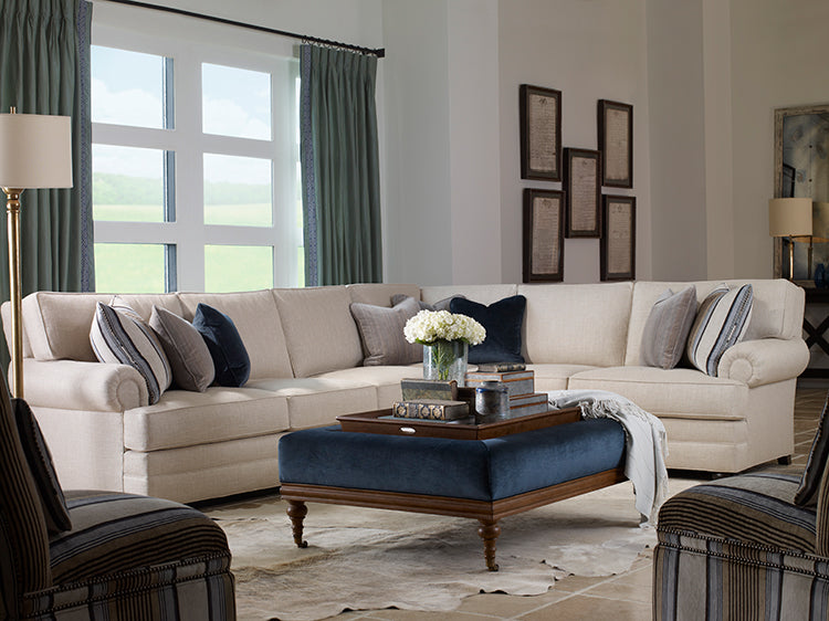 Living room with a beige sectional sofa, blue ottoman, and decorative pillows.